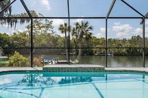 A pool with a view of a lake and trees, surrounded by a metal fence. - Crystal River Waterfront w/ Dock, Pool & Manatees! (Crystal River)