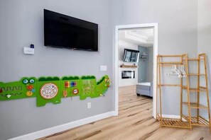 A room with a television mounted on the wall, a wooden floor, and a hallway leading to another room. - Crystal River Waterfront w/ Dock, Pool & Manatees! (Crystal River)