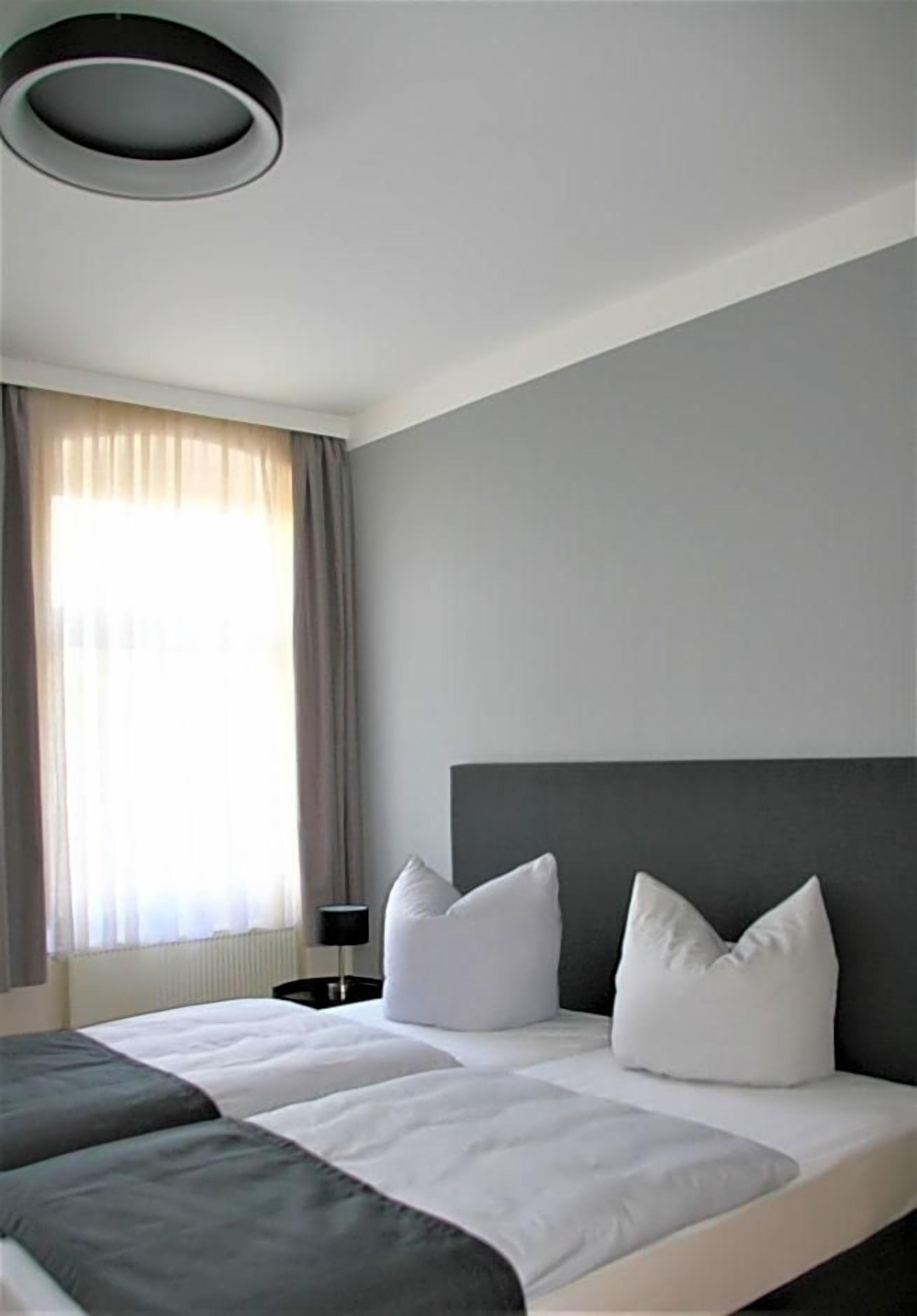 Ein Hotelzimmer mit einem großen Bett, einem Nachttisch und einer modernen Deckenleuchte.