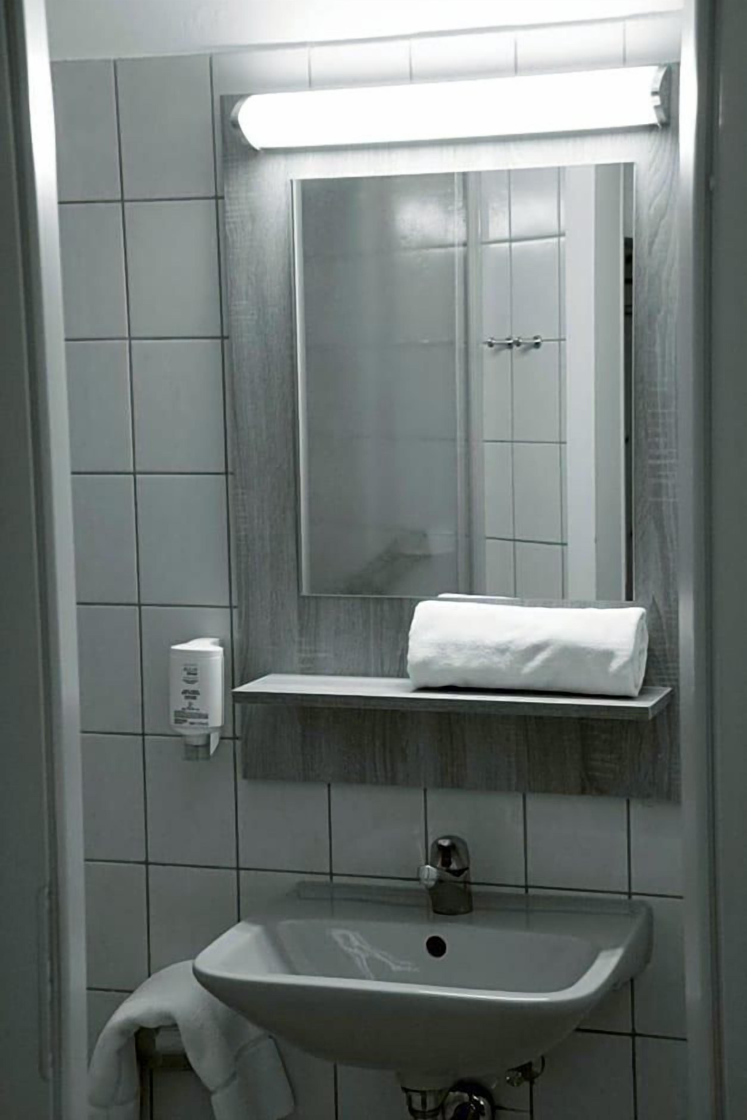 Ein Badezimmer mit einem weißen Waschbecken, einem Spiegel und einem Handtuch auf einer Ablagefläche.