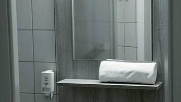 Ein Badezimmer mit einem weißen Waschbecken, einem Spiegel und einem Handtuch auf einer Ablagefläche.