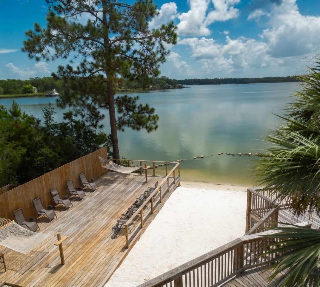 Une terrasse en bois avec des chaises longues et un hamac, donnant sur un lac paisible.