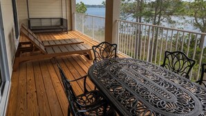 Une terrasse en bois avec une table et des chaises en métal, un banc et une balançoire.