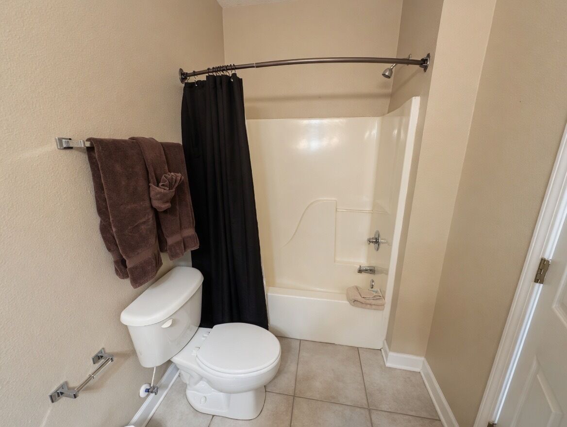 Une salle de bain équipée de toilettes, d’une baignoire et d’un rideau de douche.