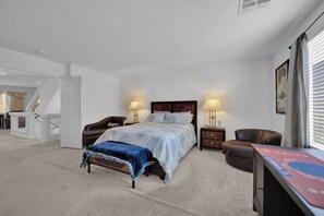 Un dormitorio con una cama, dos mesitas de noche, una silla, un escritorio y una escalera.
