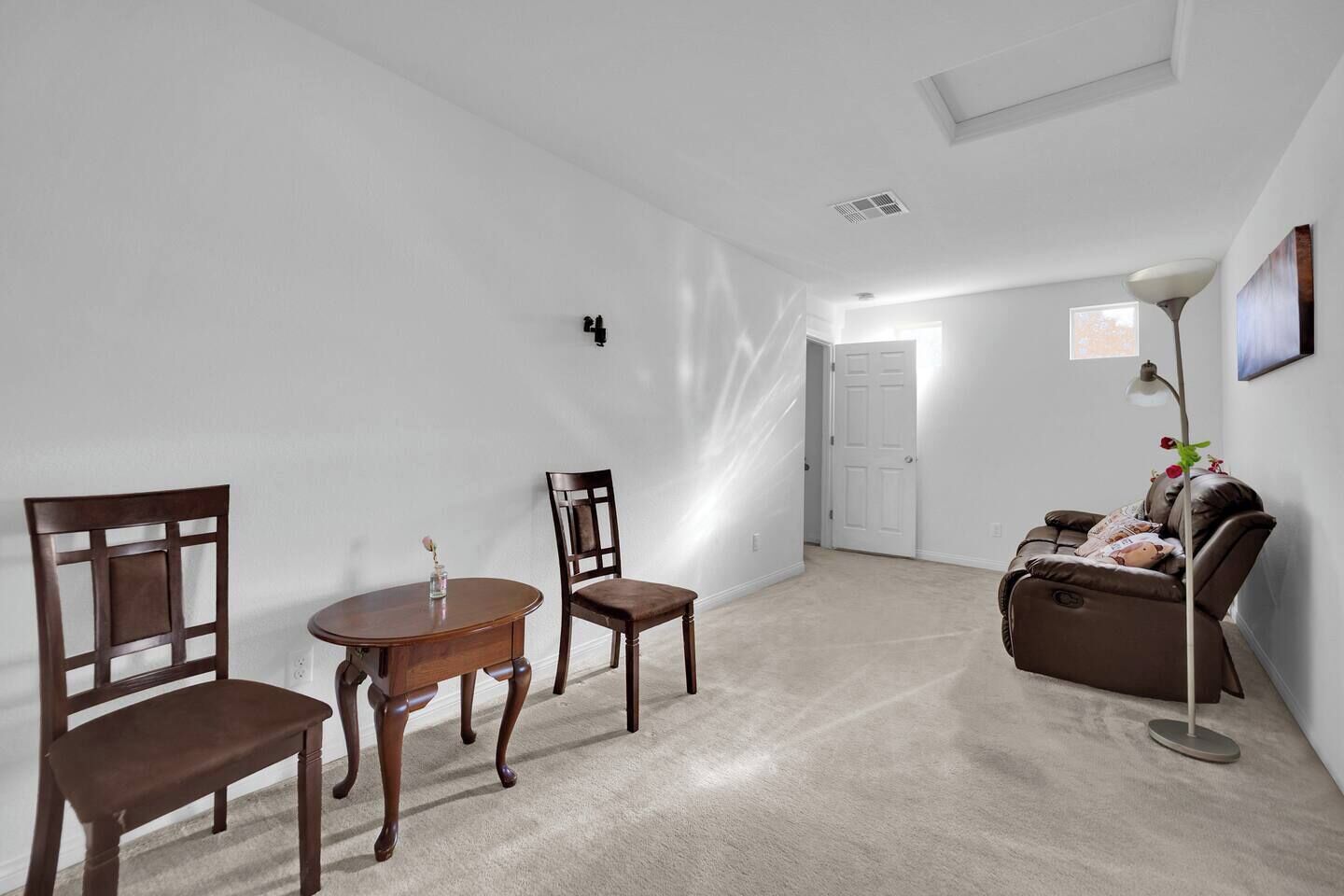 Une pièce comprenant une table ronde en bois, deux chaises, un canapé et un lampadaire.