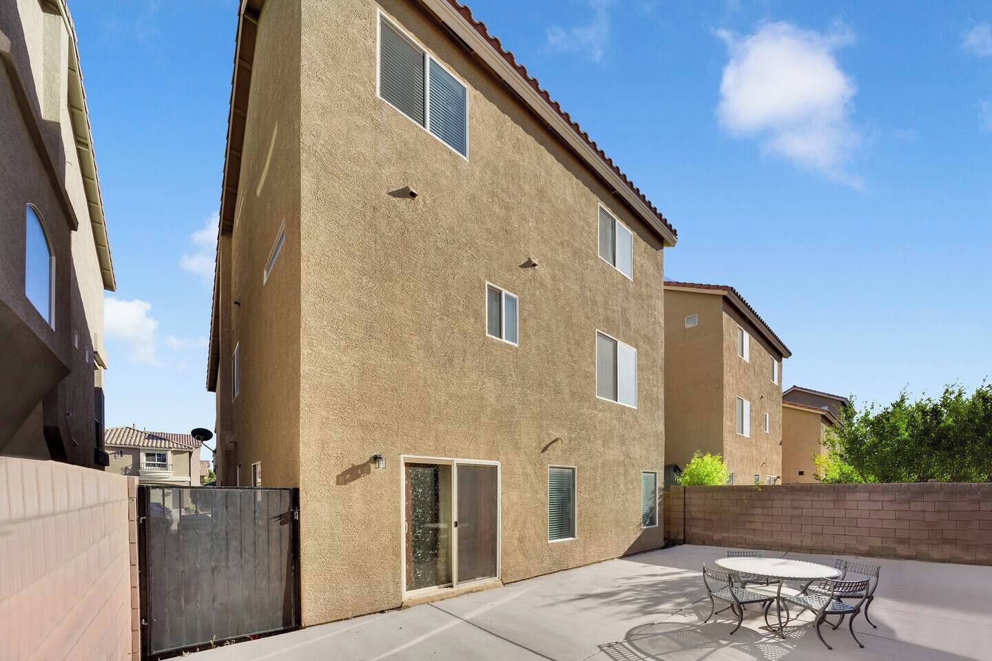 Un edificio residencial de varios pisos con un patio que tiene una mesa redonda y sillas.