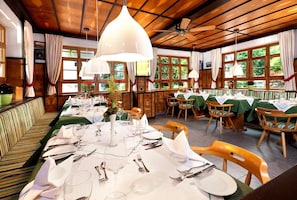 A restaurant with wooden ceilings and large windows, tables set with white tablecloths and silverware. - Edelweiss (Bad Woerishofen)