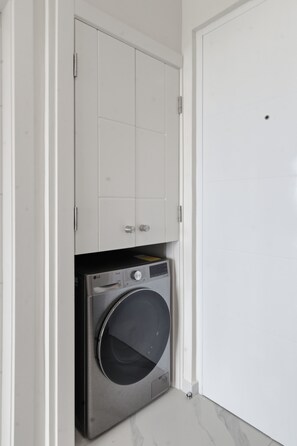 A compact laundry room with a washing machine and a cabinet above it. - Luxury Golf View Studio/Elegance&Serenity Infinity Pool (Bavaro)