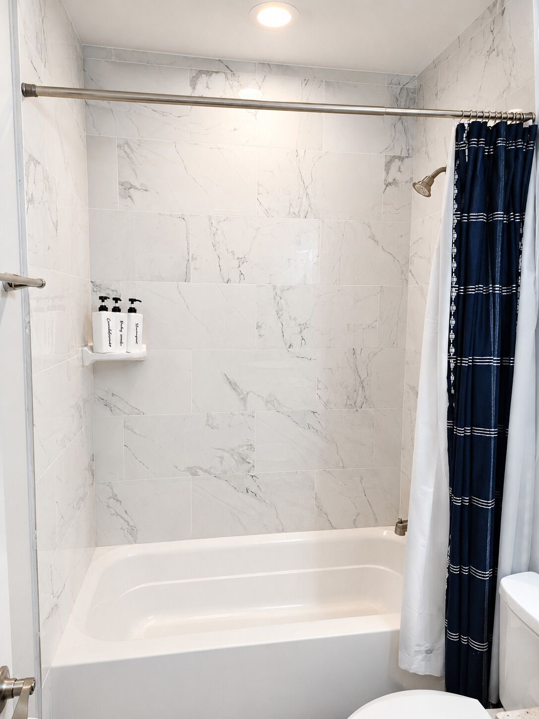 Et badeværelse med badekar, bruseområde og toilet.
