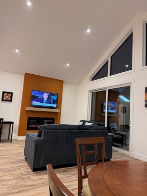 A living room with a television, a sofa, a dining table, and a fireplace.