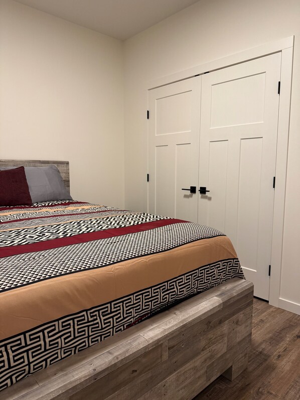 A bedroom with a bed, a wooden bench, and a white wardrobe.