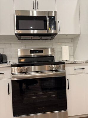 A kitchen with a stainless steel microwave, oven, and stovetop.