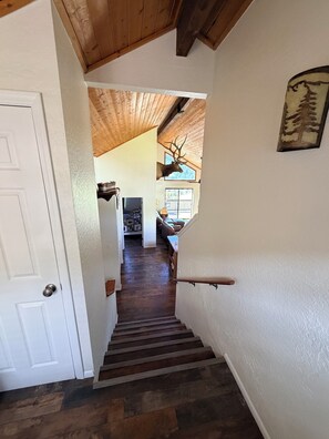 A staircase leading to a living area with a wooden ceiling and a mounted deer head. - 3-bedroom cabin in charming Pine with cozy mountain vibes and AMAZING views (Pine)