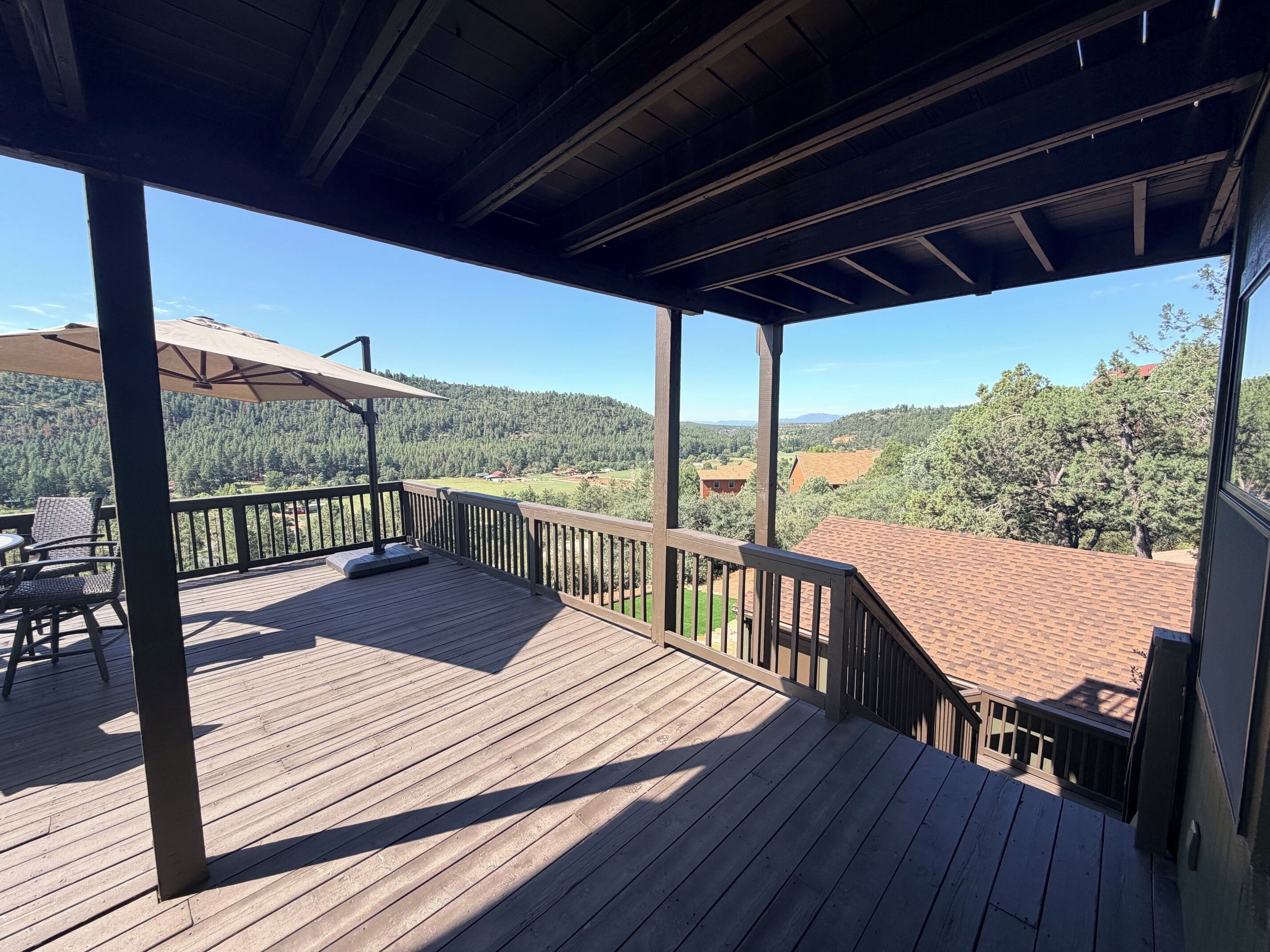 A wooden deck with a view of a forested landscape.