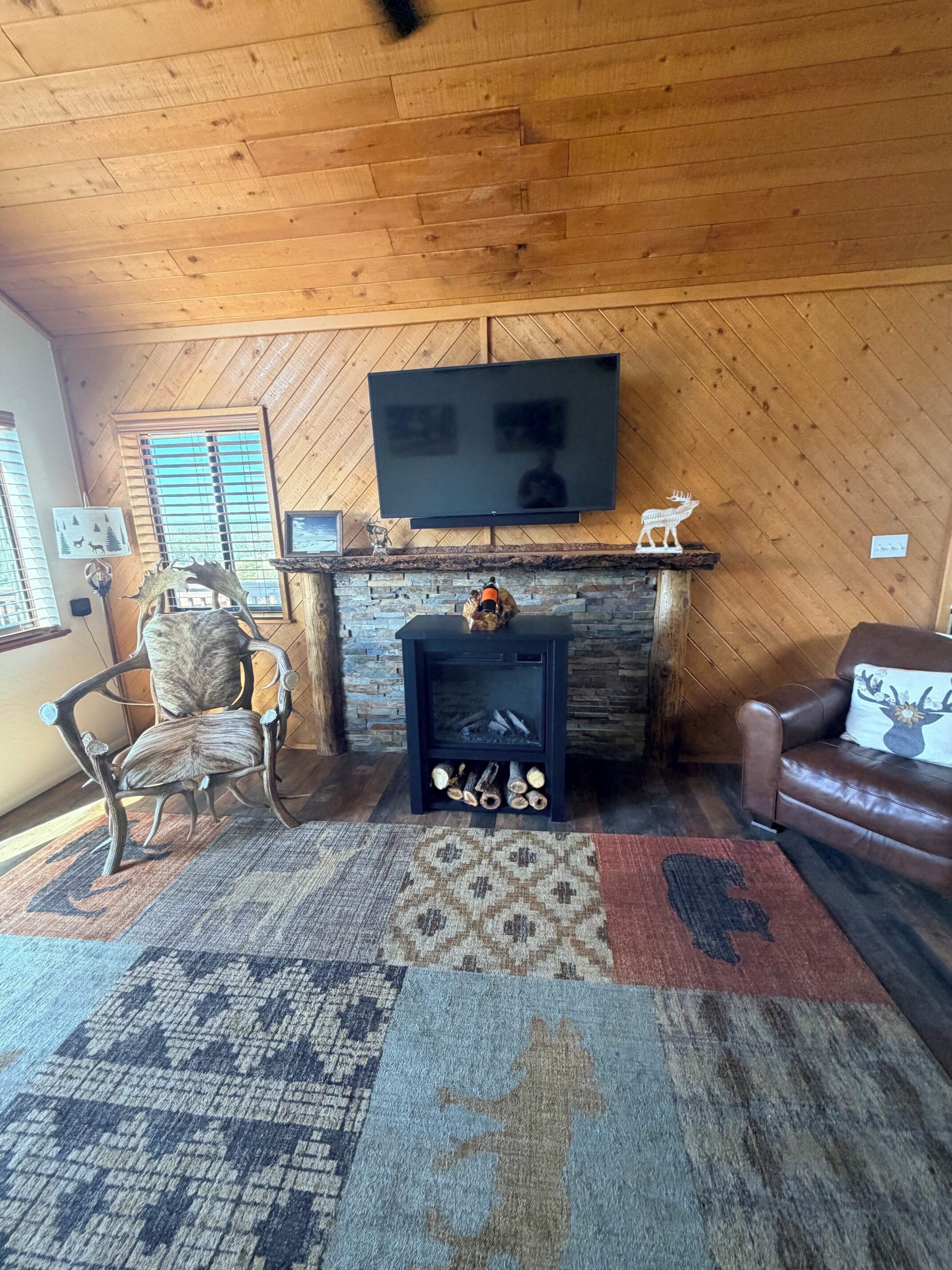 A cozy living room with a fireplace, a mounted TV, and a comfortable seating area.