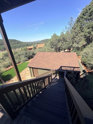 A wooden deck leading to a house with a tiled roof, surrounded by trees and a hilly landscape. - 3-bedroom cabin in charming Pine with cozy mountain vibes and AMAZING views (Pine)