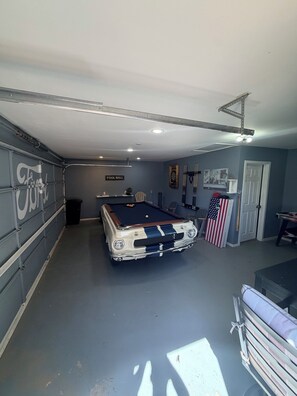 Une table de billard dans une pièce dotée d’une porte de garage, d’une porte classique et d’une horloge murale.