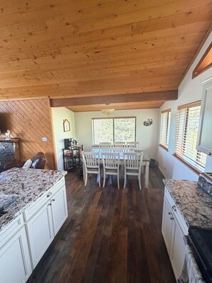 A kitchen with wooden cabinets, a dining table with chairs, and a window with blinds. - 3-bedroom cabin in charming Pine with cozy mountain vibes and AMAZING views (Pine)