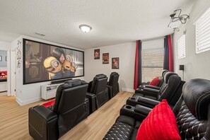Ein Wohnzimmer mit Flachbildfernseher, schwarzen Ledersofas und einem Holztisch.