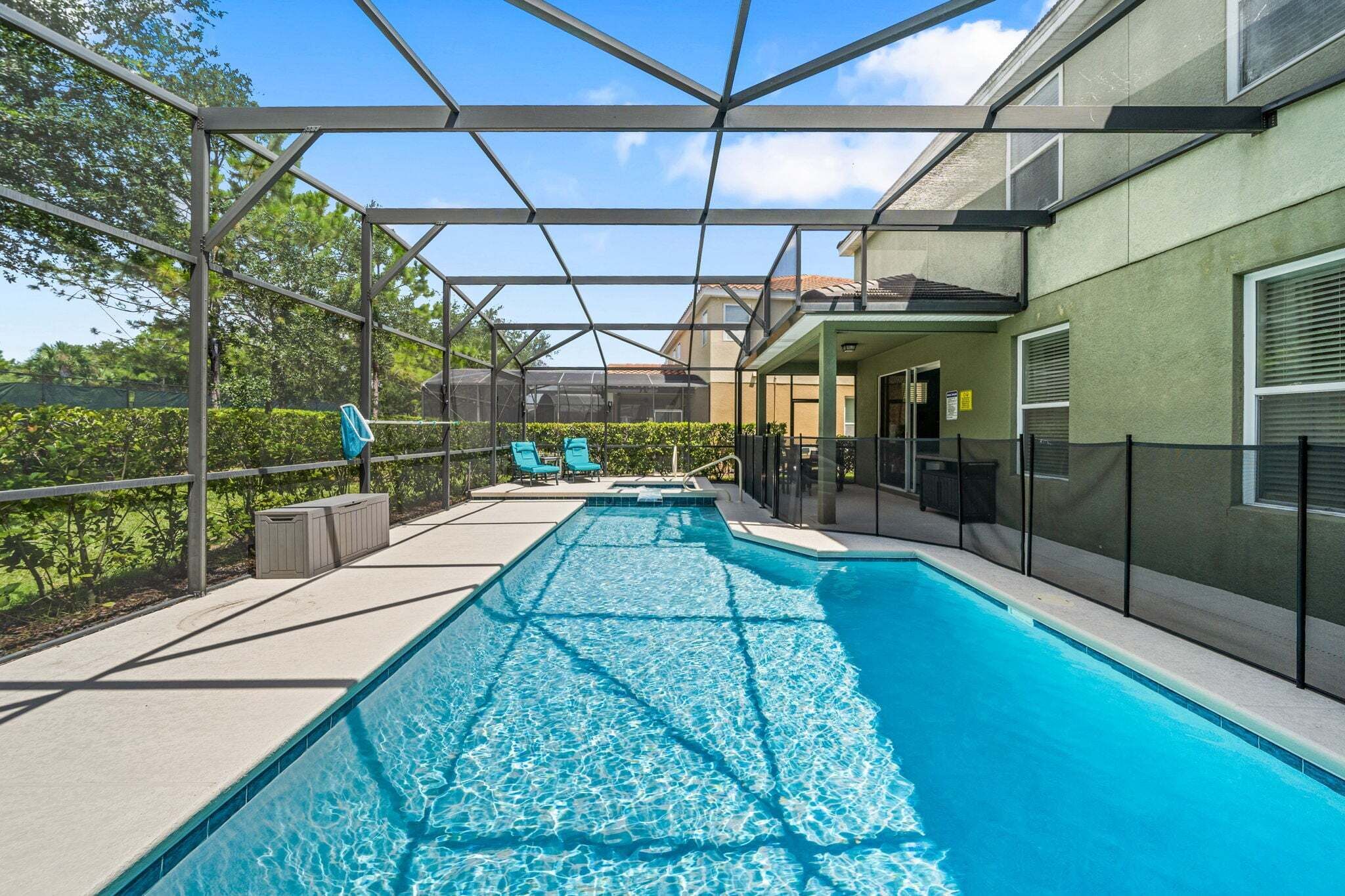 A swimming pool with a glass enclosure, surrounded by a patio area with lounge chairs and a covered seating area.