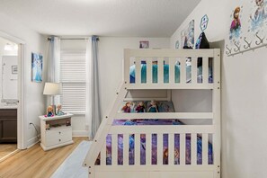 Ein Kinderzimmer mit Etagenbetten, einem Nachttisch, einer Lampe und Wanddekorationen.