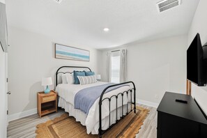 Ein Schlafzimmer mit einem Bett, einem Nachttisch, einer Lampe und einem Fernseher.