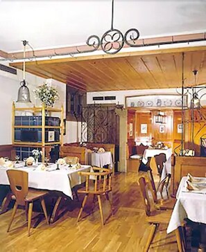 A restaurant interior with wooden flooring, tables set for dining, and hanging light fixtures. - Glocke (Rothenburg ob der Tauber)