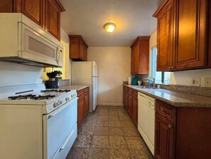 A kitchen with wooden cabinets, a stove, a microwave, and a dishwasher. - 2 Bedroom Apt 5 minutes from Rodeo Dr Walk to Restaurants and Markets (Beverly Hills)