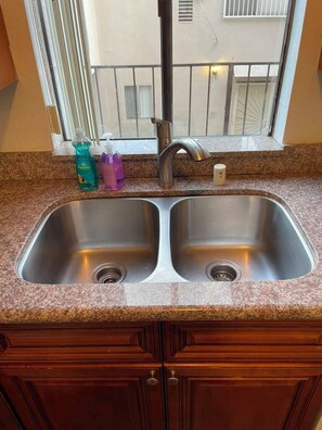 A kitchen with a double sink, granite countertop, and wooden cabinets. - 2 Bedroom Apt 5 minutes from Rodeo Dr Walk to Restaurants and Markets (Beverly Hills)