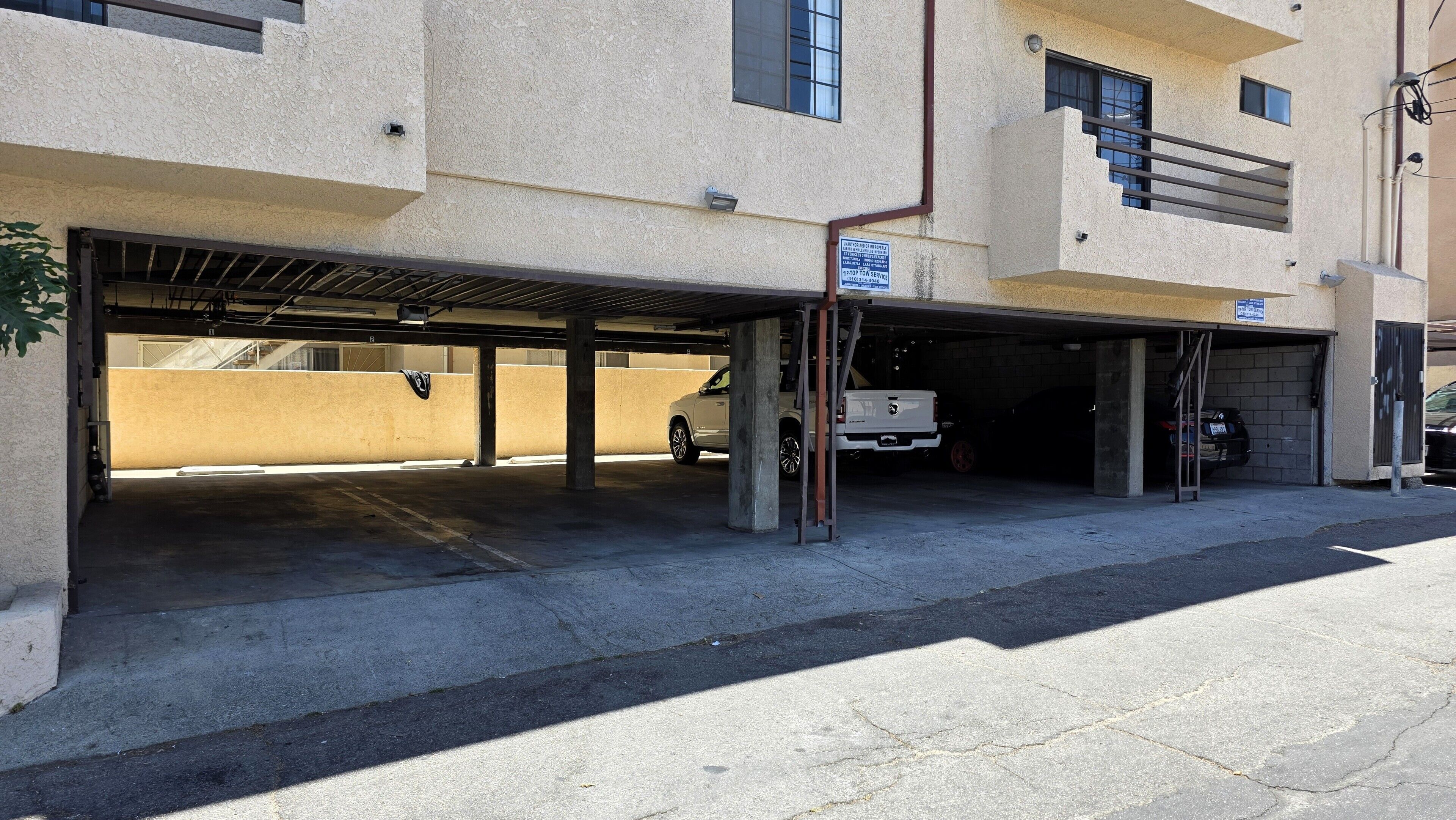 Un estacionamiento de varios niveles con pilares de concreto, área cubierta y un vehículo dentro.