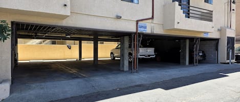 A multi-level parking garage with concrete pillars, a covered area, and a vehicle inside.