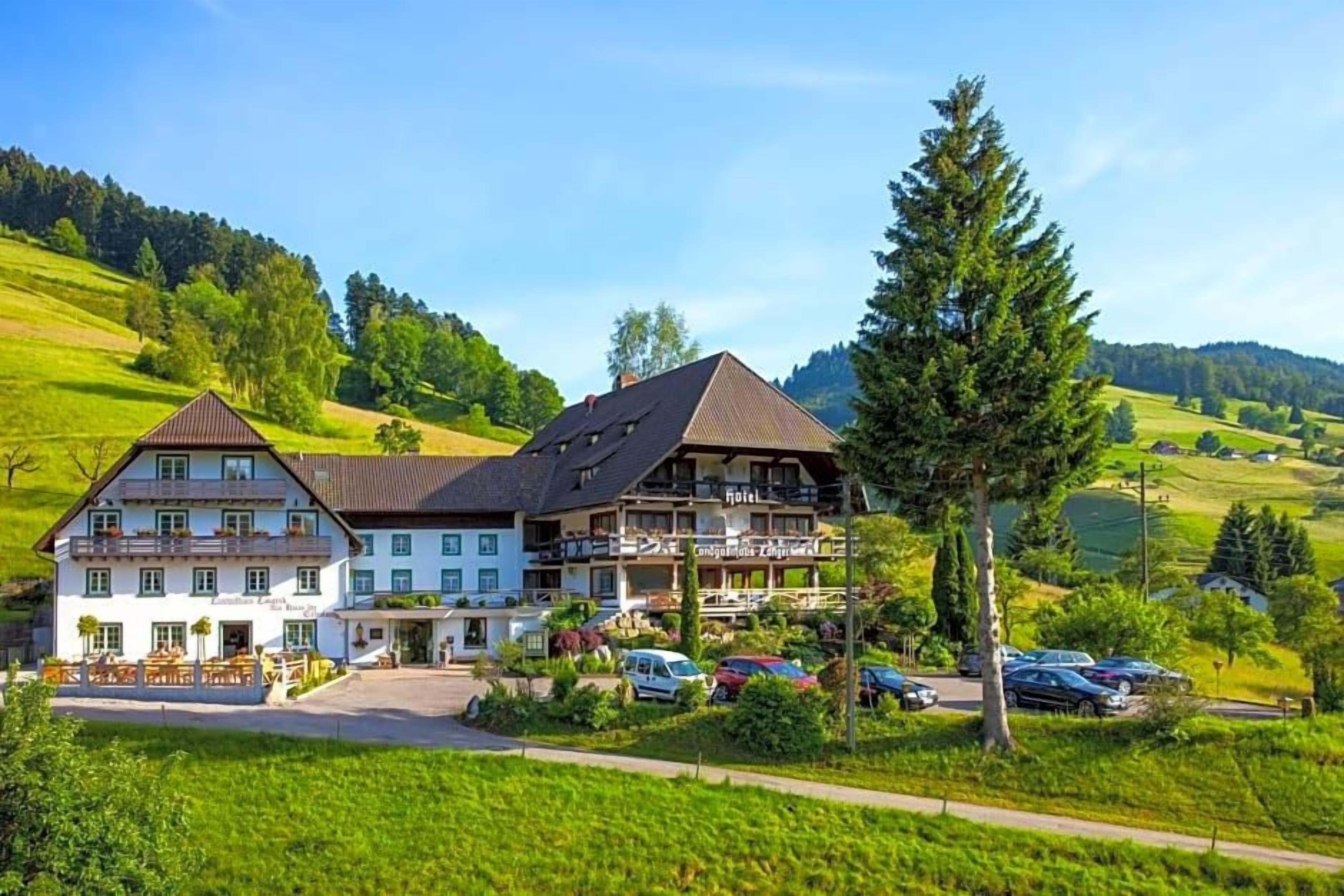 Een klassiek Europees hotel met een groot gebouw, terras en een parkeerplaats.