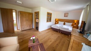 Une chambre à coucher avec un lit double, des tables de chevet, une armoire en bois et une petite table sur laquelle est posé un vase.