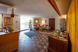 A cozy living room with a patterned floor, a wooden reception desk, and a sofa set. - Landhaus Langeck (Münstertal)