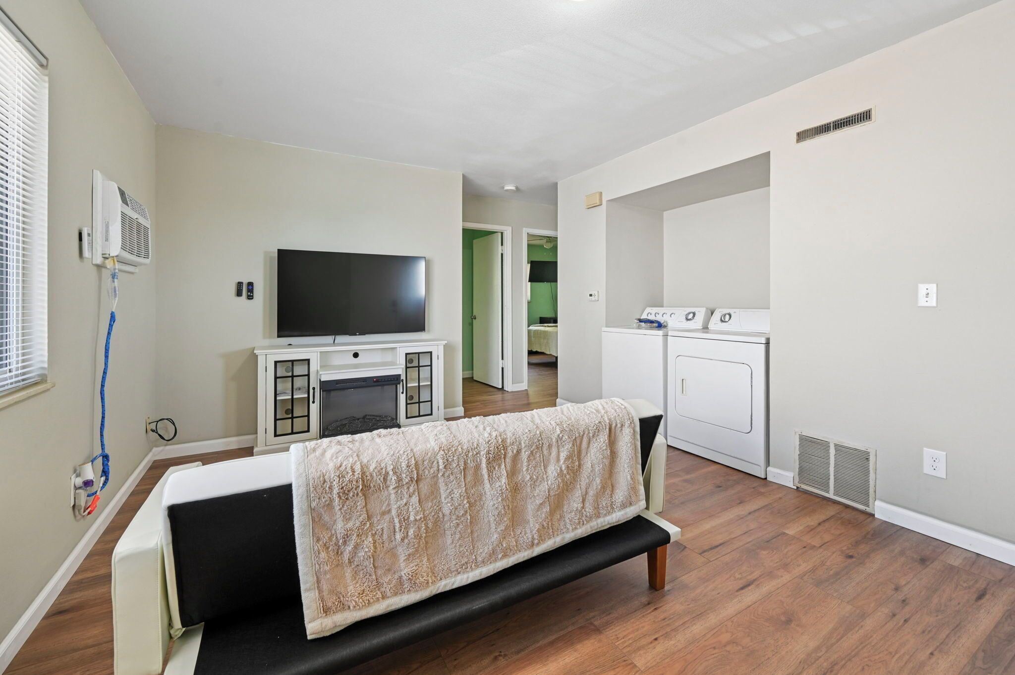 Een moderne woonkamer met een flatscreen televisie, een bank met een plaid, een ingebouwde open haard en een wasruimte met wasmachines.