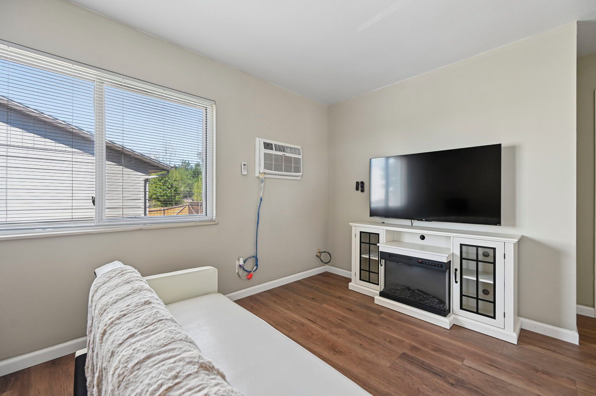 A bedroom with a bed, a TV, a fireplace, and a window with blinds.