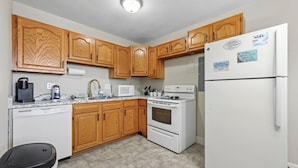 A kitchen with wooden cabinets, a white refrigerator, a stove, and a dishwasher.