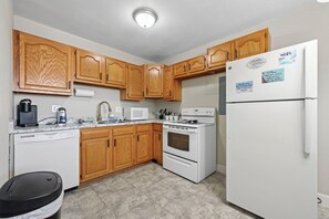 Una cocina con armarios de madera, un refrigerador blanco, una estufa y un lavavajillas.