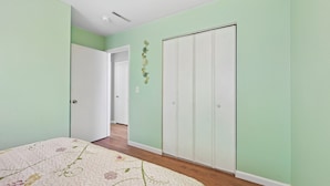 A bedroom with a bed, a wardrobe, and a door leading to another room.