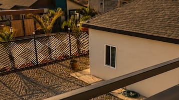 Un edificio residencial con techo inclinado, un ventanal pequeño y un área pavimentada con grava.