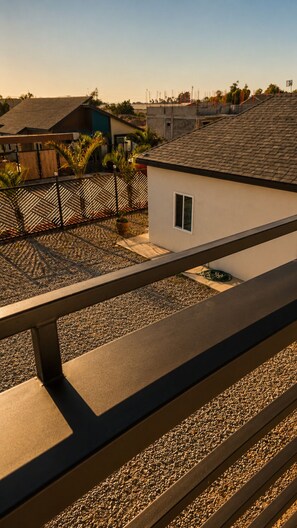 Un edificio residenziale con tetto spiovente, una piccola finestra e un’area pavimentata con ghiaia.