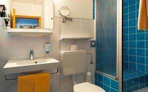 A bathroom with a white sink, toilet, and blue-tiled shower enclosure. - Schleifmühle (Holzminden)