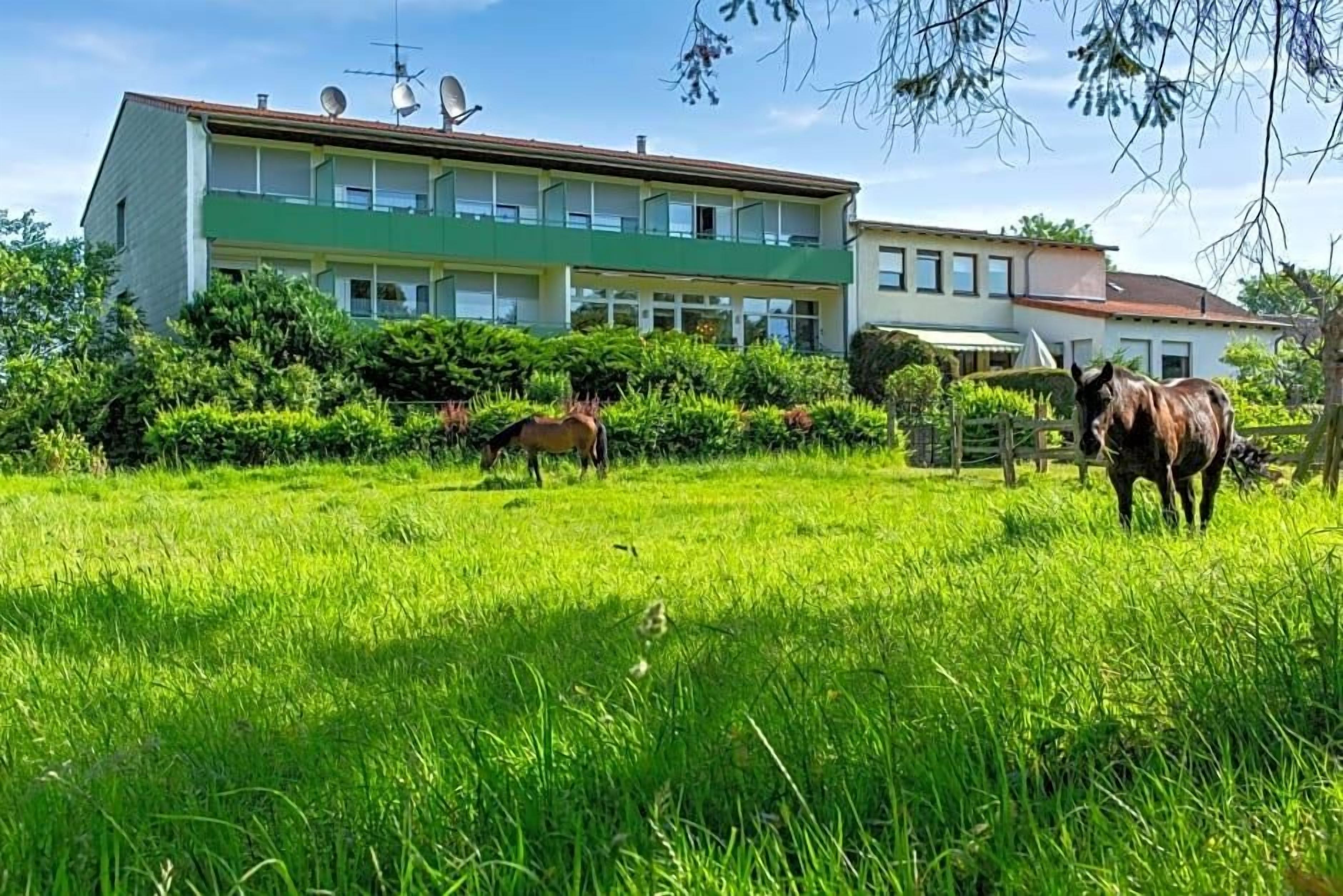 A building with multiple balconies and satellite dishes, surrounded by lush green grass and trees.