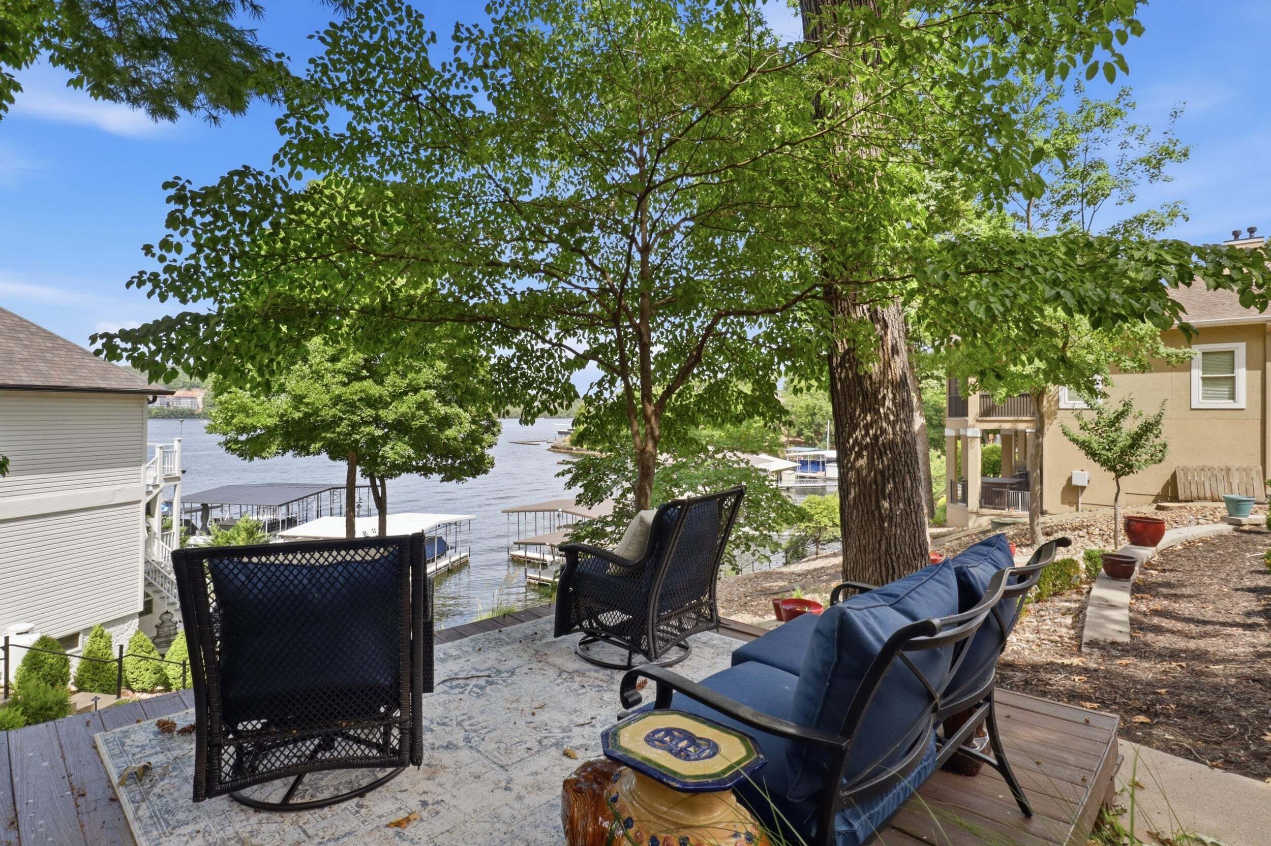 Una terraza con muebles de exterior, vista a un lago y un árbol.