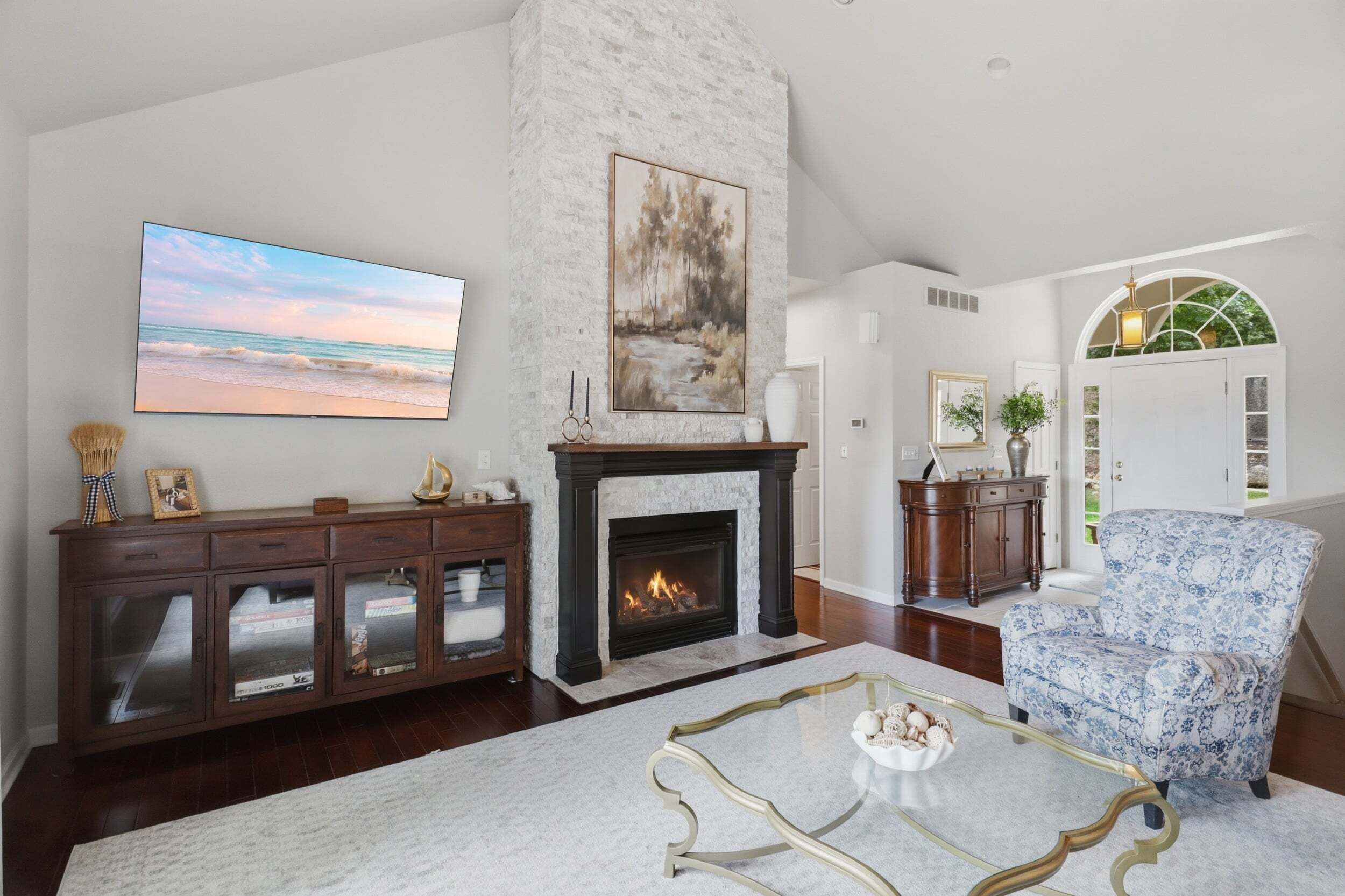 A living room with a fireplace, a television, and a view of the outdoors.