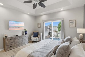 Ein Schlafzimmer mit einem großen Bett, einem Schminktisch, einem Stuhl, einem Fernseher und einem Balkon mit Blick.