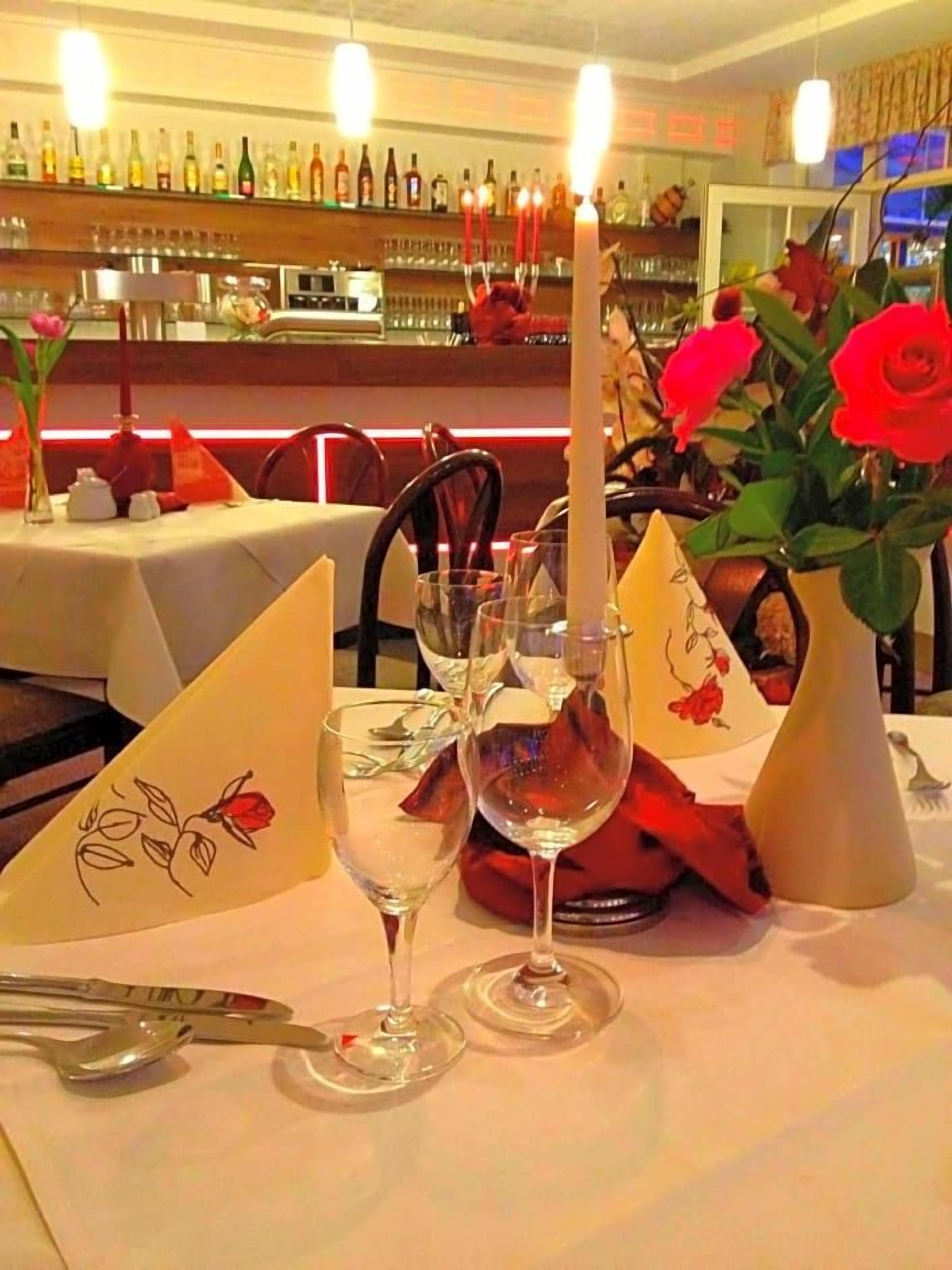 A table set for dining with wine glasses, a candle, and a vase with flowers.