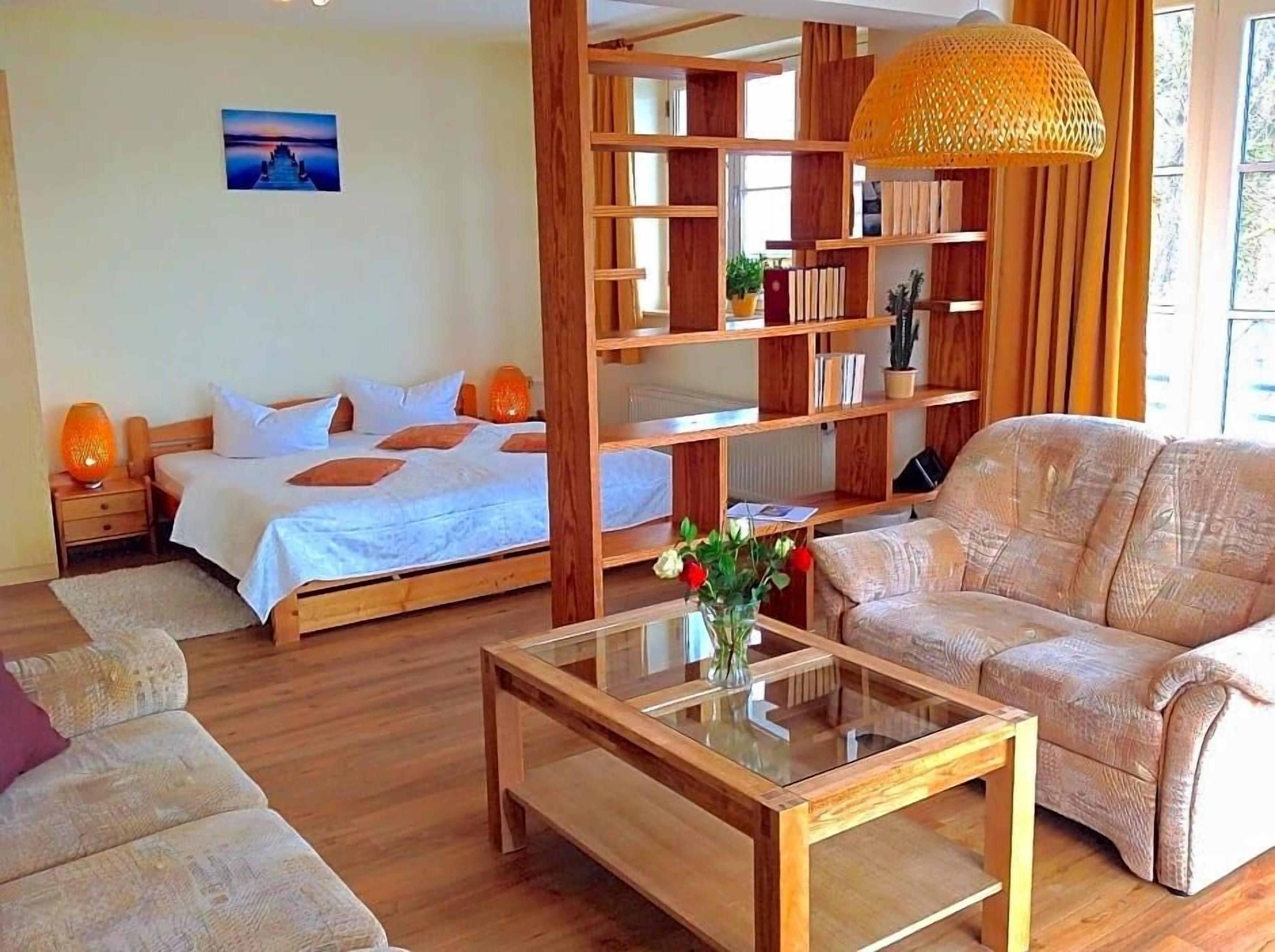 Ein Zimmer mit einem Bett, einem Sofa, einem Couchtisch und einem Bücherregal.