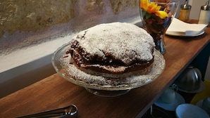 A dessert on a glass plate on a wooden table with a textured wall in the background. - Emporium Case Vacanze (Castellammare del Golfo)